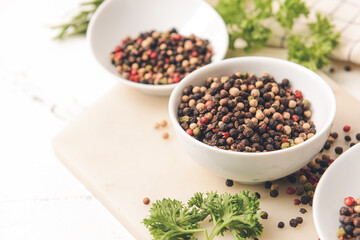 Bowls with peppercorns on light background