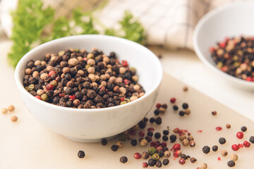 Bowl with peppercorns on light background