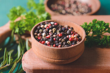 Bowl with peppercorns on color background