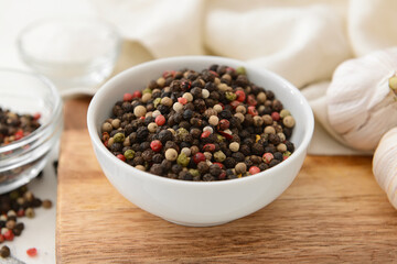 Bowl with peppercorns on wooden background