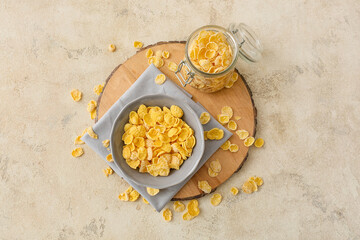 Bowl and jar with tasty cornflakes on light background