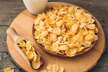 Plate and scoop with tasty cornflakes on wooden background
