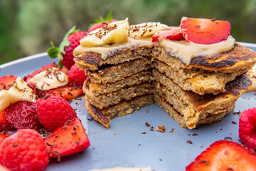 Healthy banana oatmeal pancakes stack sliced with strawberries, bananas, raspberries, chocolate and halva spread. Easy gluten free morning breakfast or brunch. Delicious fluffy pancakes heap, Vibrant.