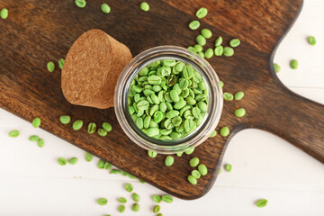 Jar with green coffee beans on light background
