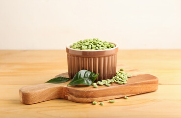 Bowl with green coffee beans on wooden background