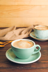 Cups of hot cappuccino on wooden background