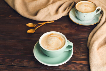Cups of hot cappuccino on wooden background