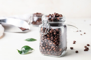 Fototapeta na wymiar Jar with coffee beans on light background