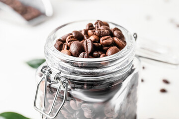 Jar with coffee beans on light background, closeup