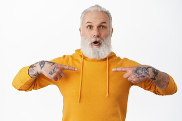 Surprised mature bearded guy with tattoos pointing at himself, gasping amazed in disbelief, being...