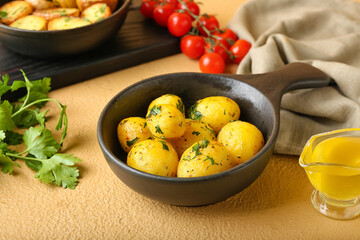 Frying pan of tasty baked potatoes with parsley on color background