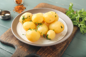 Naklejka na ściany i meble Plate of tasty boiled potatoes with parsley on color wooden background