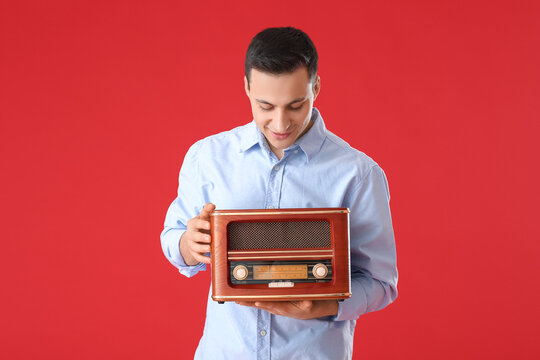 Young man with retro radio receiver on color background