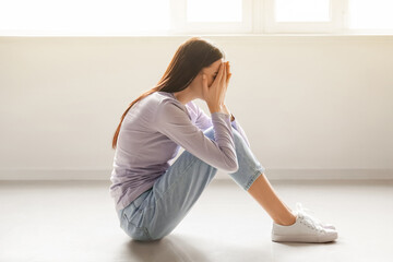 Sad woman sitting on floor in empty room