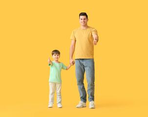 Happy father and his little son showing thumb-up on color background