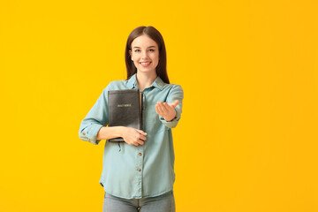 Young woman with Bible on color background