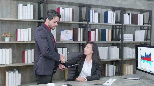 Businessman and his co-worker making a successful offer on the table in modern office.