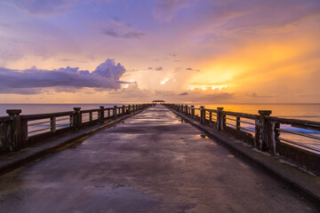 Fototapeta na wymiar Bridge on beach in sunset and sea wave.