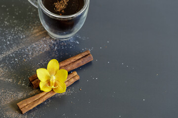 Cinnamon sticks and a glass cup of coffee espresso decorated with an orchid flower