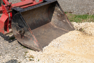 focus on metal bucket of backhoe digging yellow gravel