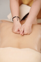 Masseuse doing pushing motion when massaging clients back along spine