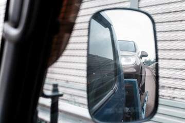View from car side mirror of tow truck towing a broken down car on the highway