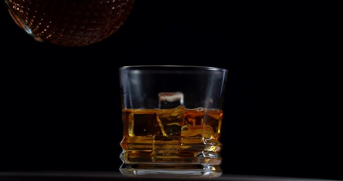 a man's hand pours whiskey into a rotation glass