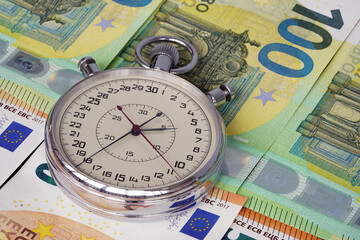 Money macro shot. The stopwatch lies in the center of the banknote layer. Clock. Time is money                                                              