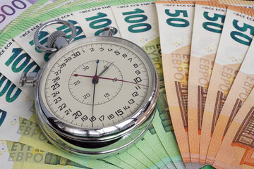 Money macro shot. The stopwatch lies in the center of the banknote layer. Clock. Time is money                                                              