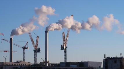 Pollution de l'air par deux cheminées d'usine (incinérateur) crachant des volutes de fumée blanche dans le ciel bleu, à Ivry-sur-Seine / Paris XIII (France)