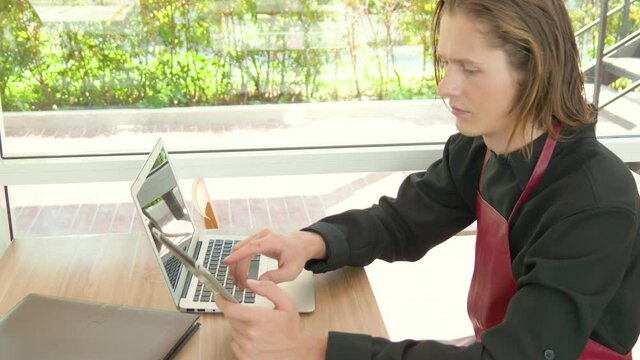 businessman typing his tablet along with using laptop on table in modern office.