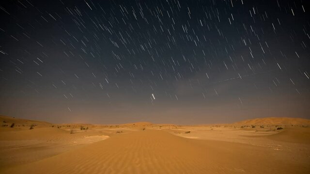 Scenic night sky with star trails at sand dunes desert