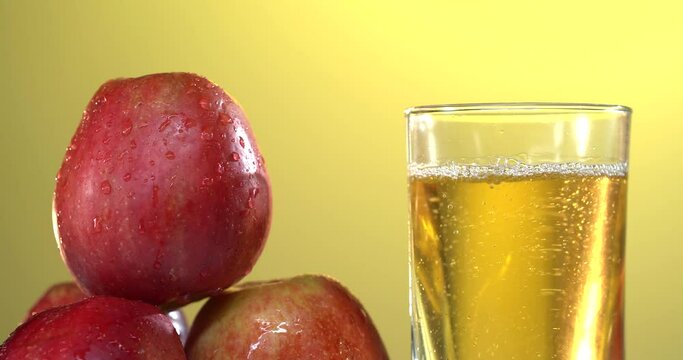 close-up of pouring juice into a glass. there are fresh red apples on the table nearby. 4k video