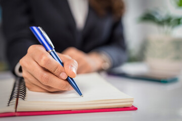 Business woman writing something on notebook. Close-up