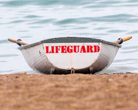 An iconic lifeguard skiff sits on the beach, bow pointed to the water in Toronto's Beaches neighbourhood.