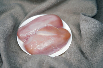 Chicken fillet on a white round plate top view. Raw meat. Food preparation.                               