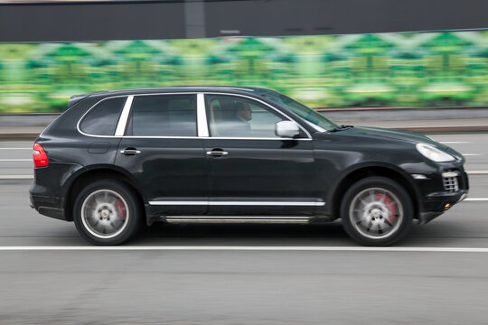 Man Driving Old Porsche Cayenne 955. Black Used SUV Rides On Street On High Speed