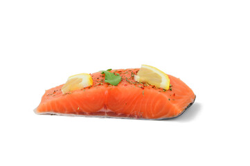 A piece of red fish sprinkled with seasoning with lemon slices and a green leaf. Salmon fillets
