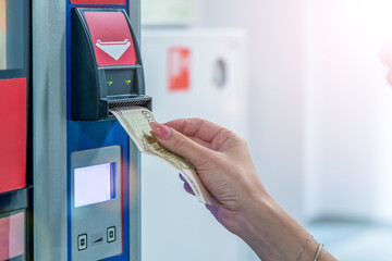 Woman inserts a 100 ruble banknote into a currency validator to pay for her drink at a vending...