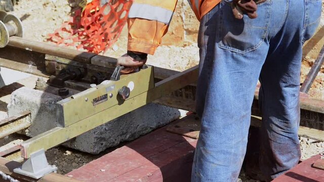 construction of railway track with wooden sleepers. Worker with a drill makes the hole in which the bolt that holds the rail fixed on the sleeper will be fixed.