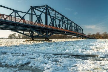 steel bridge over a frozen river with snow ice floes