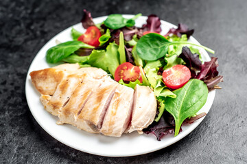 Chicken fillet with salad and spinach. Healthy food on stone background
