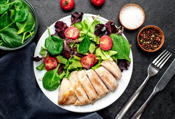 Chicken fillet with salad and spinach. Healthy food on stone background