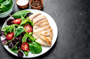 Chicken fillet with salad and spinach. Healthy food on stone background with copy space for your text