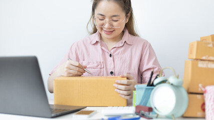 Young Asian woman is writing down the customer's details and addresses on the Clipboard in order to...