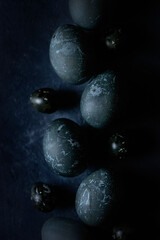 eggs painted dark blue on a black background