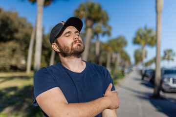 Obraz premium Peaceful man standing with palm trees and blue sky as background