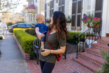 Beautiful happy mother holding her cute baby in peaceful neighborhood