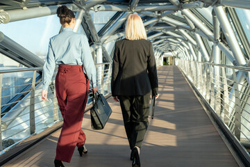 rear view of contemporary businesswomen walking along modern building