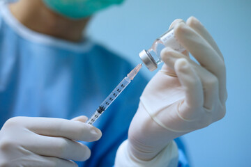 doctor holds syringe and vaccine bottle for infection cure (Focus at syringe). Concept of...